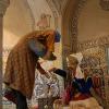 Manikin of a man about to leave the public bath with clothes warped in a special cloth (under arm) receiving fragrant rose water from a worker to make him smell good 